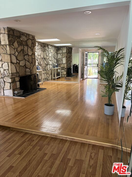 interior space with wood-type flooring and a stone fireplace