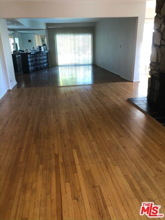 unfurnished living room featuring dark hardwood / wood-style floors and a stone fireplace