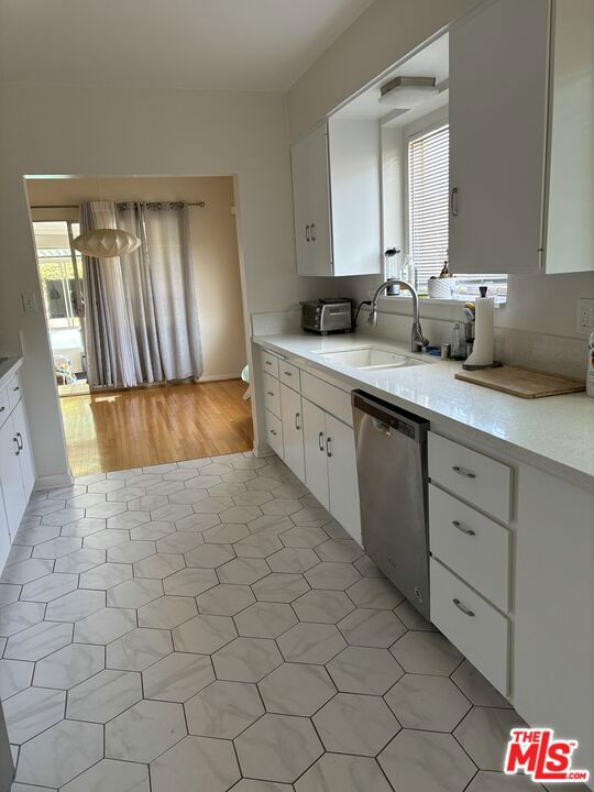 kitchen featuring dishwasher, light wood-type flooring, sink, and white cabinetry