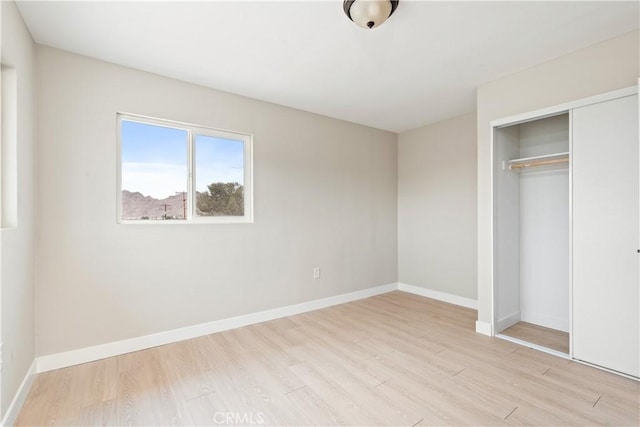 unfurnished bedroom with light hardwood / wood-style flooring and a closet