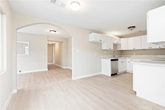 kitchen with light hardwood / wood-style floors, white cabinetry, stainless steel dishwasher, and sink