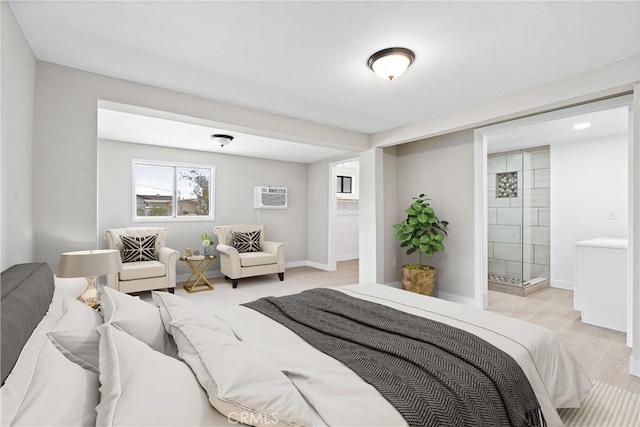 bedroom featuring a wall mounted AC, ensuite bathroom, and light wood-type flooring