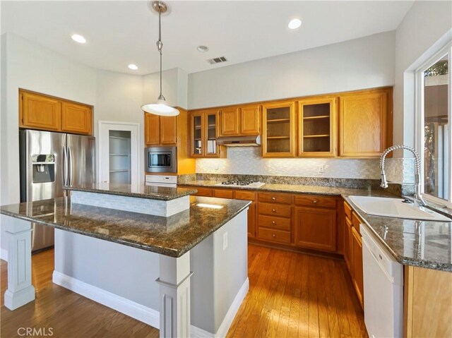 kitchen featuring dark hardwood / wood-style flooring, stainless steel appliances, sink, a kitchen island, and hanging light fixtures