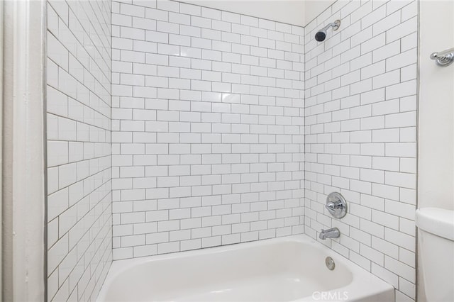 bathroom with tiled shower / bath combo and toilet