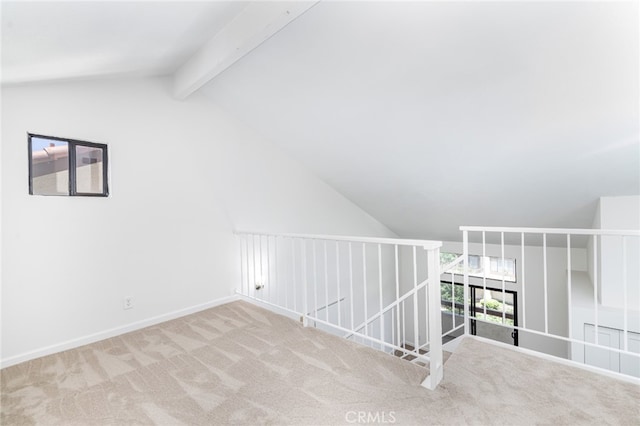 additional living space featuring vaulted ceiling with beams and light carpet