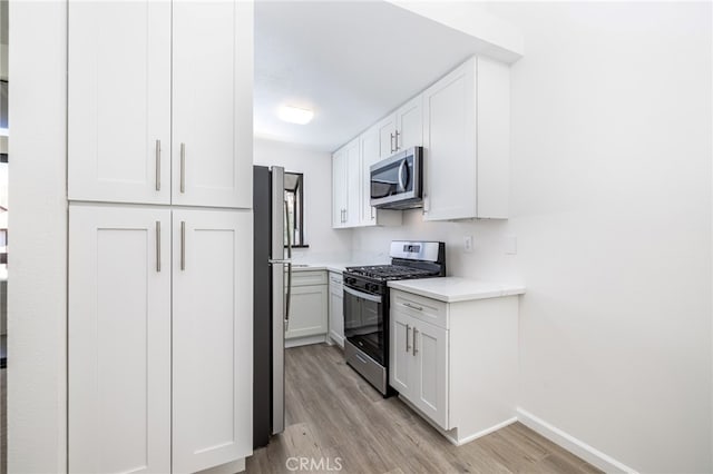 kitchen with white cabinets, stainless steel appliances, and light hardwood / wood-style flooring