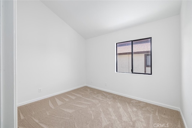 spare room featuring light colored carpet and lofted ceiling