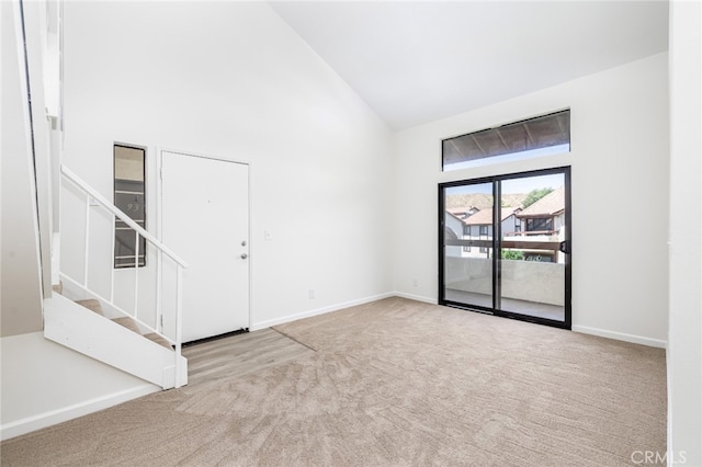 carpeted empty room with high vaulted ceiling