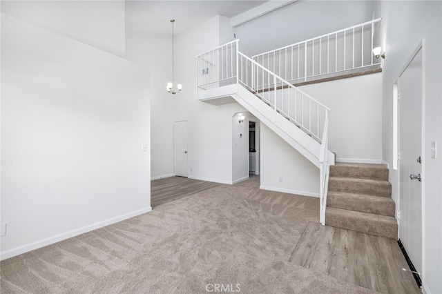 unfurnished living room with wood-type flooring, a high ceiling, and a notable chandelier