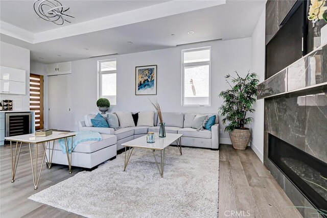 living room featuring light hardwood / wood-style flooring, beverage cooler, and a healthy amount of sunlight