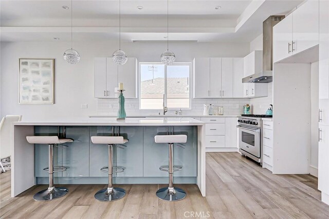 kitchen with white cabinets, decorative light fixtures, a breakfast bar, and high end stainless steel range