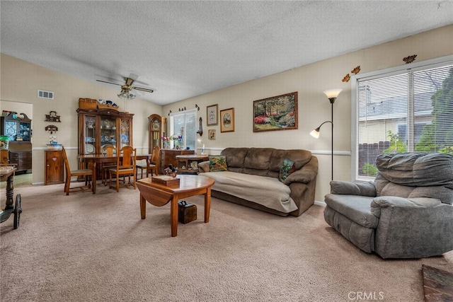 carpeted living room with a textured ceiling, vaulted ceiling, and ceiling fan