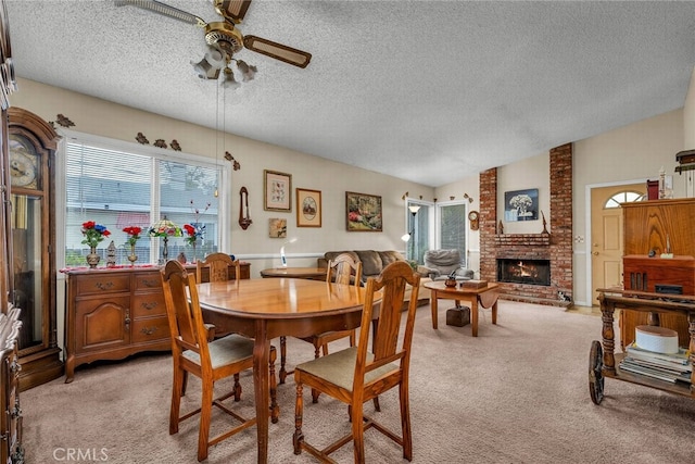 carpeted dining space featuring ceiling fan, lofted ceiling, a textured ceiling, and a fireplace