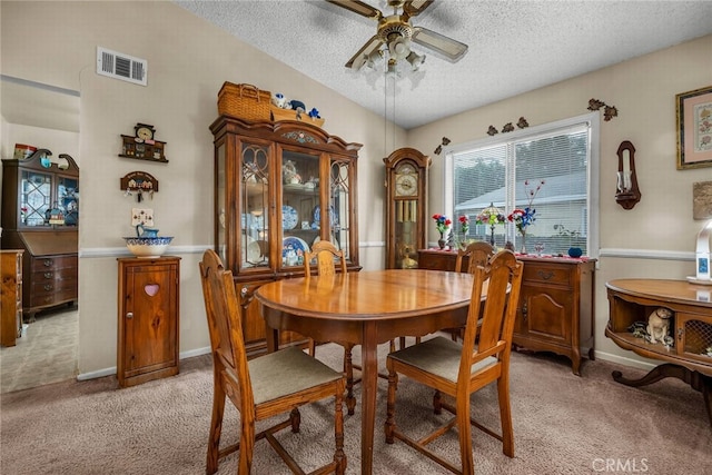 dining room with a textured ceiling, ceiling fan, and light colored carpet