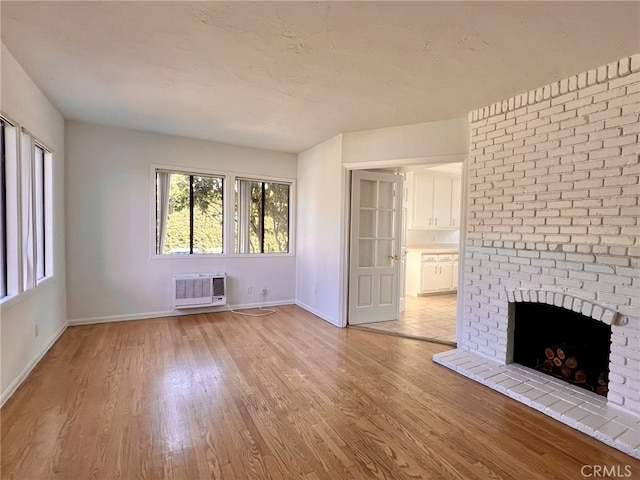 unfurnished living room featuring hardwood / wood-style flooring, a fireplace, and an AC wall unit