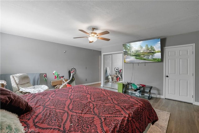 bedroom with a textured ceiling, ceiling fan, and dark wood-type flooring