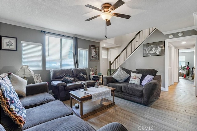 living room with a textured ceiling, light hardwood / wood-style floors, ceiling fan, and ornamental molding