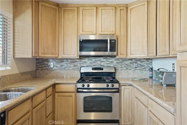 kitchen featuring decorative backsplash, light stone counters, stainless steel appliances, and light brown cabinetry