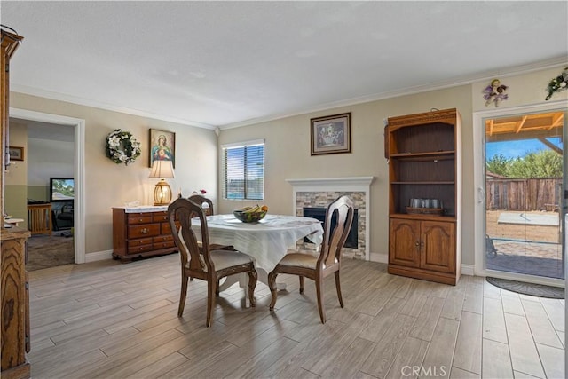 dining area featuring a stone fireplace, light wood-type flooring, and a wealth of natural light