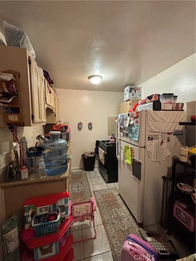 kitchen featuring light tile patterned flooring, black range with gas cooktop, and white refrigerator