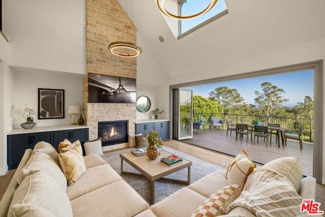 living room featuring hardwood / wood-style flooring, a chandelier, a brick fireplace, and high vaulted ceiling