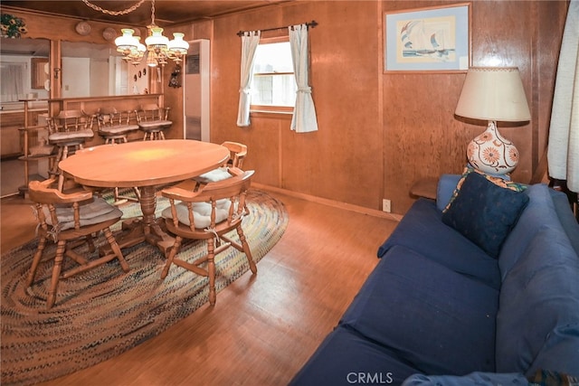 dining room featuring a notable chandelier, wood-type flooring, and wood walls