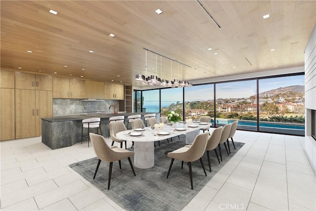 dining space featuring sink, a wall of windows, wooden ceiling, a mountain view, and light tile patterned flooring