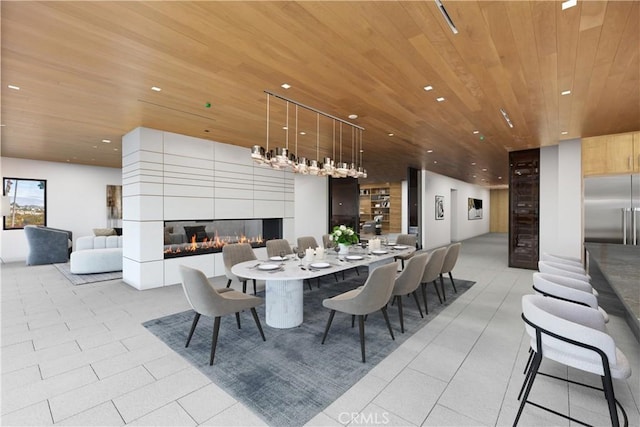 dining area featuring wood ceiling and a tile fireplace