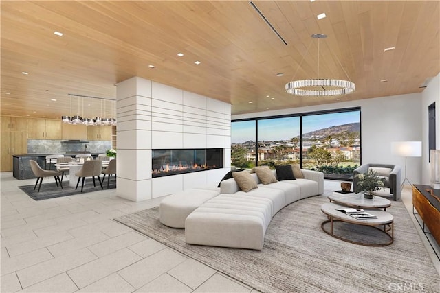 living room with a tile fireplace, an inviting chandelier, and wood ceiling