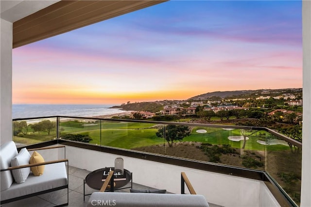 balcony at dusk featuring a water view