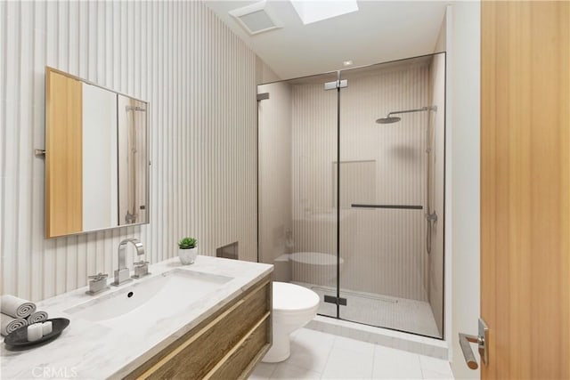 bathroom with a skylight, walk in shower, tile patterned flooring, toilet, and vanity