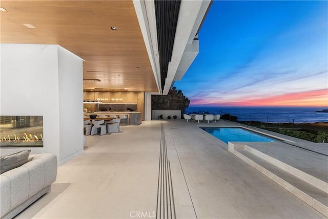 13 Ritz Cove Dr, Dana Point, CA 92629 - pool at dusk with a warm lit fireplace, an outdoor kitchen, and an outdoor pool