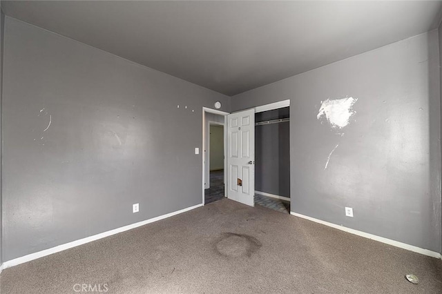 unfurnished bedroom with a closet and dark colored carpet