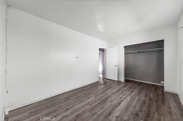 unfurnished bedroom featuring a closet and dark wood-type flooring