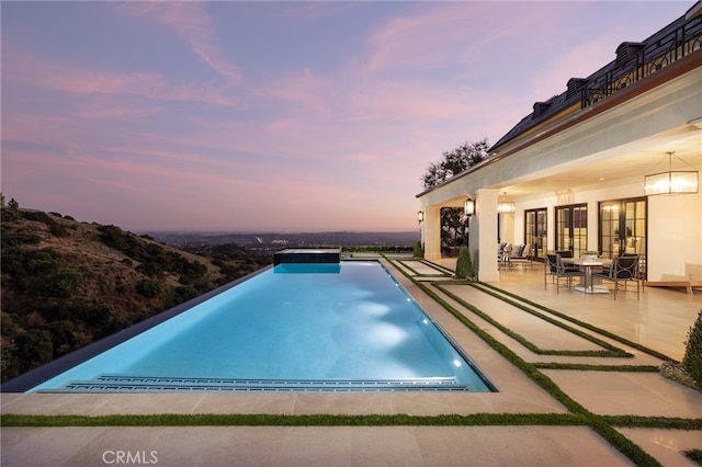 pool at dusk with a patio area