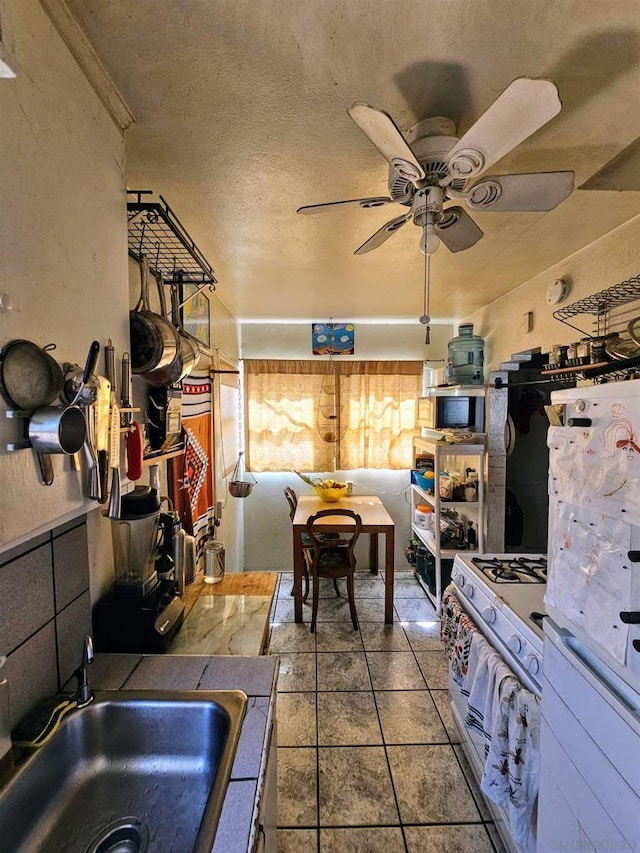 kitchen with ceiling fan, tile counters, sink, a textured ceiling, and white appliances