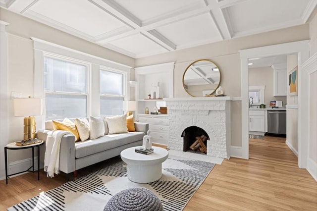 living room featuring a brick fireplace, beamed ceiling, coffered ceiling, and light hardwood / wood-style floors