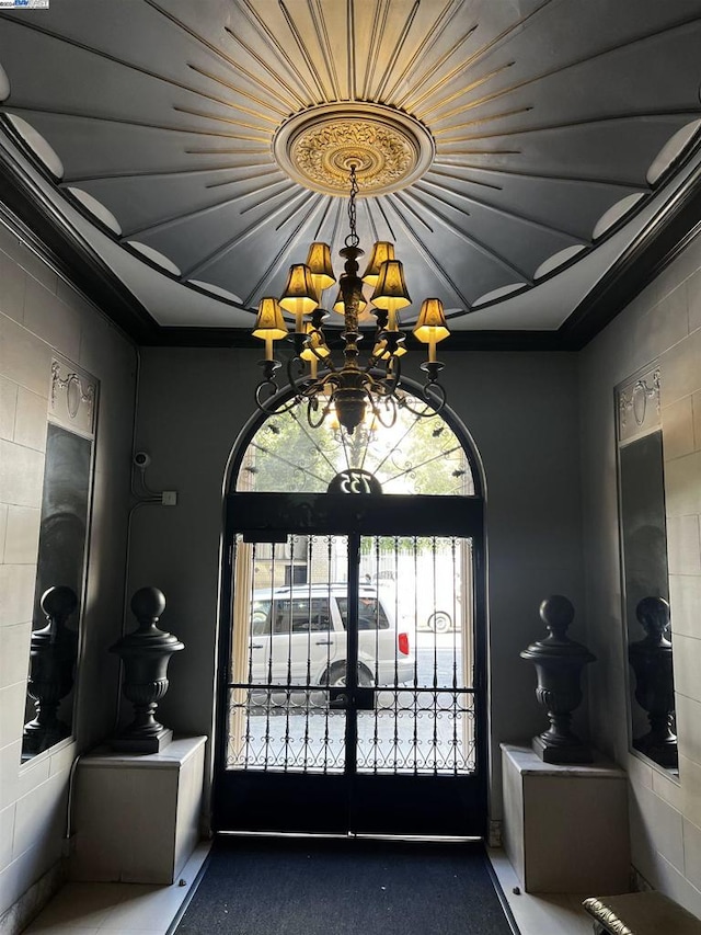 foyer featuring french doors, an inviting chandelier, and ornamental molding