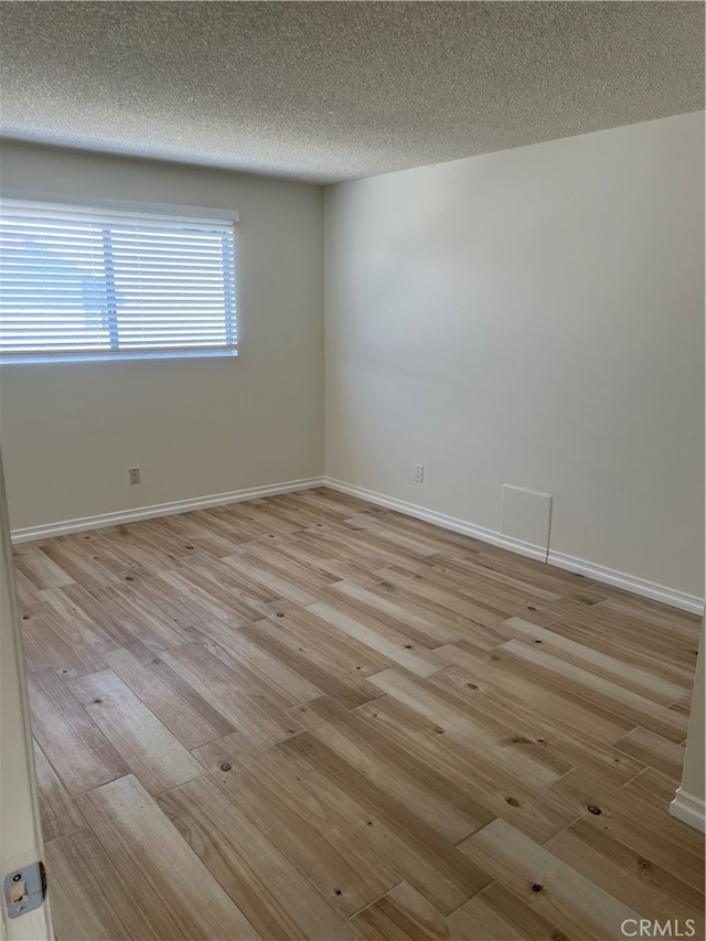 empty room featuring light wood-type flooring and a textured ceiling