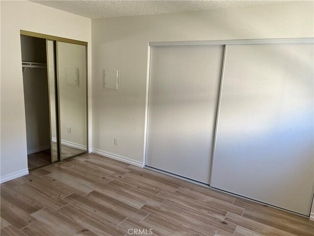 unfurnished bedroom with a textured ceiling and light hardwood / wood-style floors