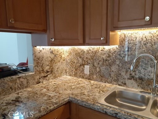 room details featuring backsplash, sink, and light stone counters