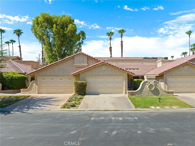 77640 Woodhaven Dr N, Palm Desert, CA 92211 - view of front of home featuring stucco siding, a tile roof, roof mounted solar panels, and concrete driveway