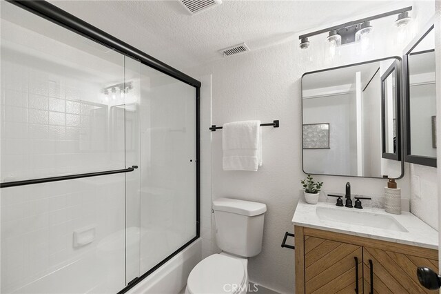 full bathroom with shower / bath combination with glass door, a textured ceiling, vanity, and toilet