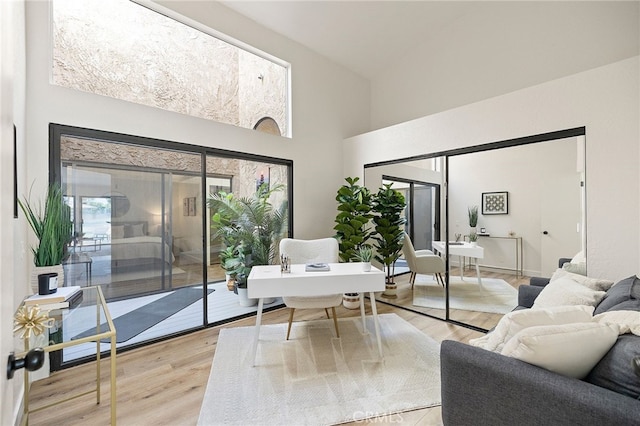 77640 Woodhaven Dr N, Palm Desert, CA 92211 - living area featuring a desk, healthy amount of natural light, a towering ceiling, and light wood-style floors