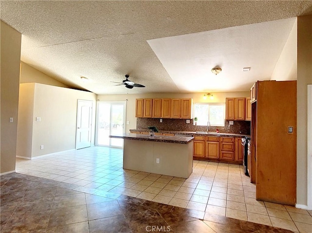 kitchen featuring backsplash, ceiling fan, a kitchen island with sink, sink, and light tile patterned flooring