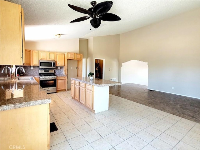 kitchen featuring high vaulted ceiling, sink, a textured ceiling, light brown cabinetry, and stainless steel appliances