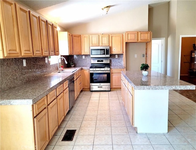 kitchen featuring light tile patterned flooring, sink, vaulted ceiling, a kitchen island, and stainless steel appliances