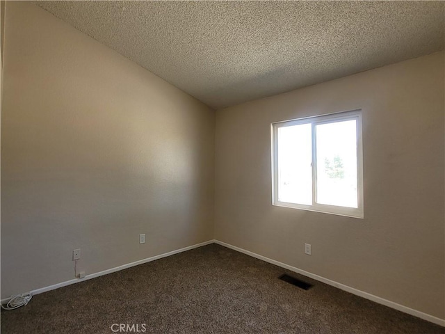 unfurnished room featuring a textured ceiling and dark carpet