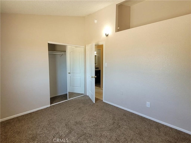 unfurnished bedroom featuring a textured ceiling, carpet floors, high vaulted ceiling, and a closet