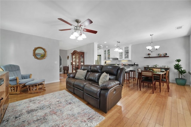 living room with ceiling fan with notable chandelier and light wood-type flooring